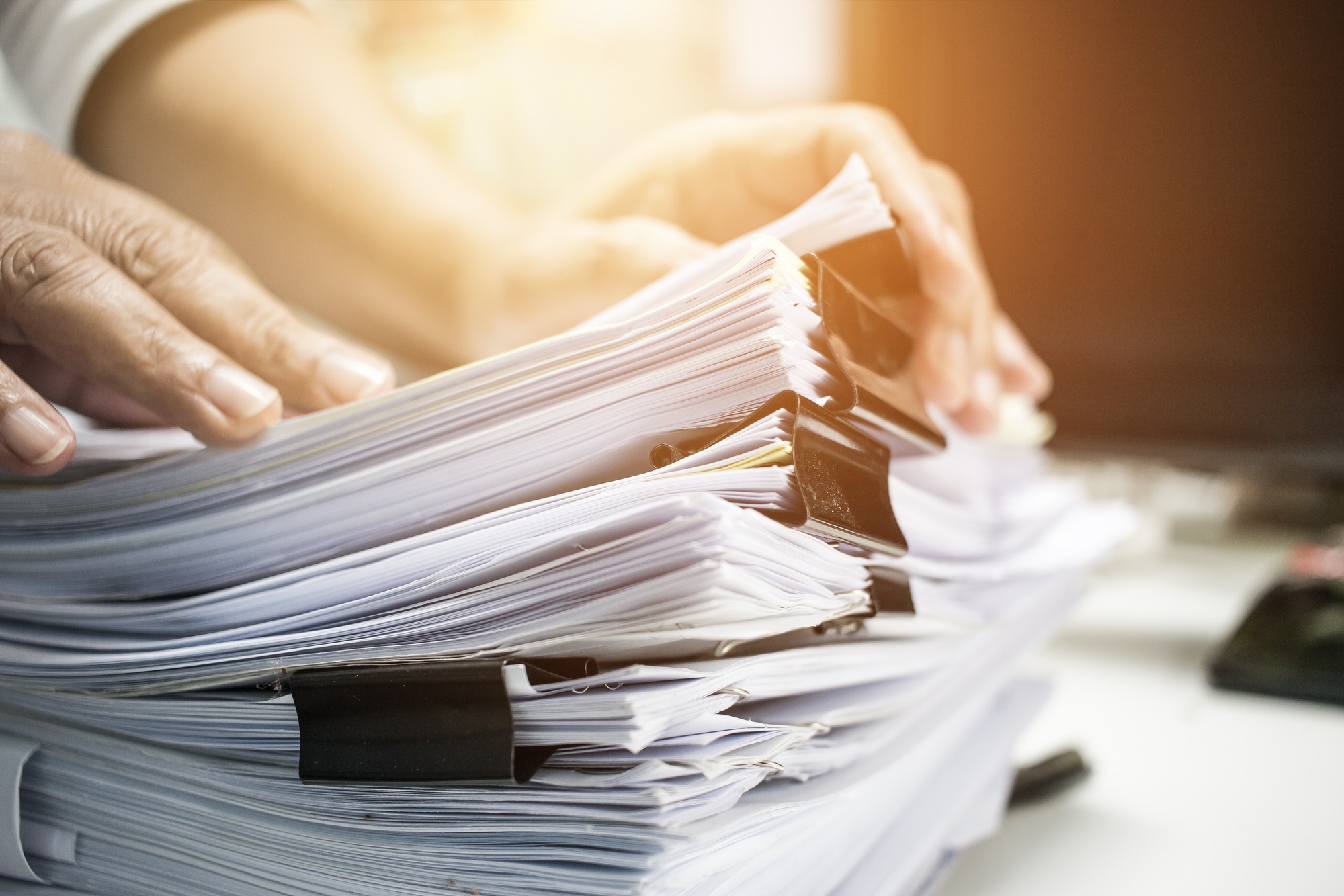 Businessman hands working in stacks of paper files