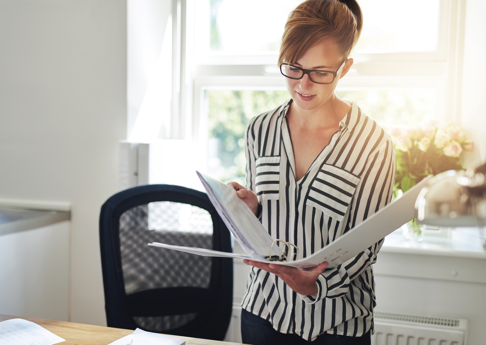 Young business woman standing in her home office reading notes